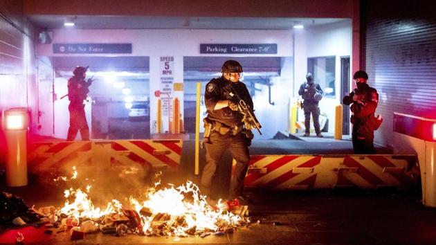 A Department of Homeland Security officer emerges from the Mark O Hatfield United States Courthouse after demonstrators lit a fire in Portland, Ore. (AP Photo)
