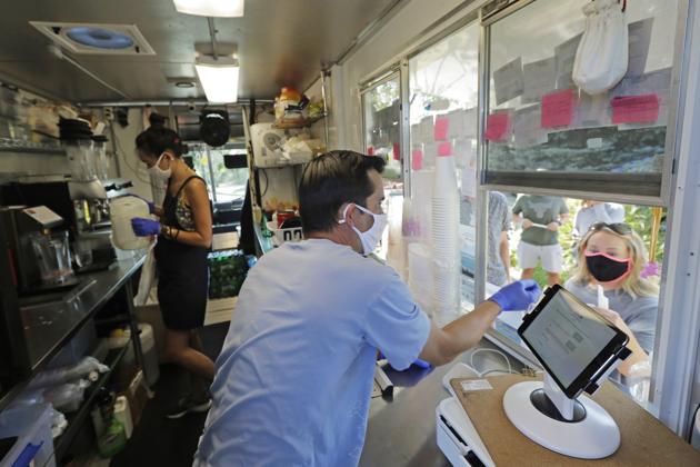 Athan Freitas, center, and Kaye Fan, left, make drinks and take orders in their Dreamy Drinks food truck, Monday, Aug. 10, 2020, near the suburb of Lynnwood, Wash., north of Seattle. Long seen as a feature of city living, food trucks are now finding customers in the suburbs during the coronavirus pandemic as people are working and spending most of their time at home.(AP)