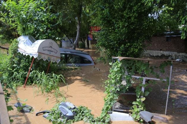 Cars, scooters and a cart under water near the Baltana police chowki after heavy rains in the region.(Keshav Singh/HT)