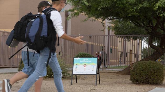 Students pass a social distancing sign while arriving at an elementary school in Surprise, Arizona, US.(Bloomberg) Students pass a social distancing sign while arriving at an elementary school in Surprise, Arizona, US.(Bloomberg)