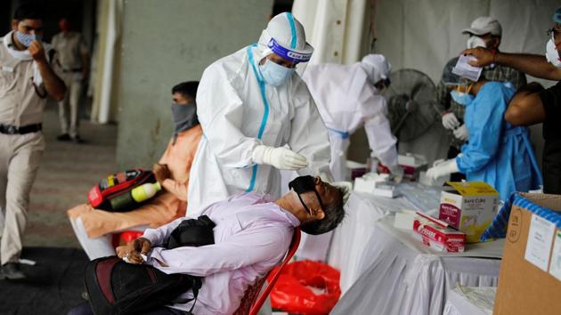 A healthcare worker wearing personal protective equipment (PPE) takes a swab from a migrant worker who returned to Delhi. (REUTERS) A healthcare worker wearing personal protective equipment (PPE) takes a swab from a migrant worker who returned to Delhi. (REUTERS)