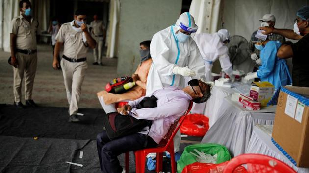 A healthcare worker wearing personal protective equipment (PPE) takes a swab from a migrant worker, who returned to Delhi from his native state, for a rapid antigen test at a bus terminal, amidst the coronavirus disease (Covid-19) outbreak in New Delhi.(REUTERS)