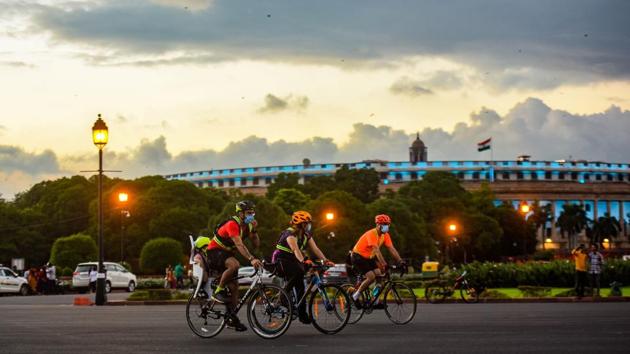Cyclists ride past Parliament House on August 23. An AQI reading between 0 and 50 is considered ‘good’ with no health impact. A reading of ‘51-100’ is considered ‘satisfactory’, which means it may have a minimal impact on the health of people with sensitivities such as chronic breathing difficulties. (Amal KS / HT Photo)