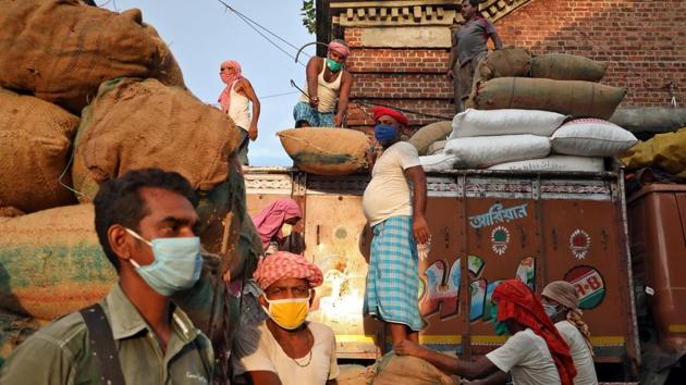 Labourers wearing protective face masks load grocery items onto a supply truck at a wholesale market during the coronavirus disease (Covid-19) outbreak in Kolkata.(REUTERS)