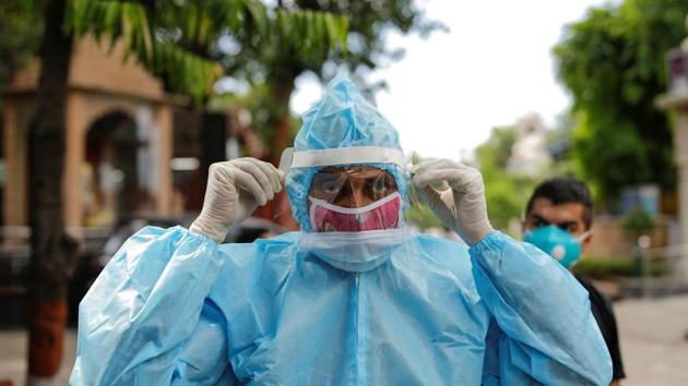 A relative wearing personal protective equipment (PPE) adjusts his protective face shield before the cremation of a man who died due to coronavirus disease at a crematorium in New Delhi.(REUTERS) A relative wearing personal protective equipment (PPE) adjusts his protective face shield before the cremation of a man who died due to coronavirus disease at a crematorium in New Delhi.(REUTERS)