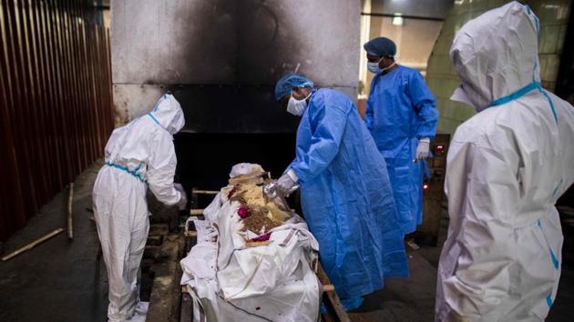 Relatives (in white) along with workers (in blue) wearing Personal Protective Equipment (PPE) prepare the body of a person who died from Covid-19 before cremation in New Delhi on August 22. The death toll from the pathogen stands at 56,706 after 912 fatalities were reported from across the country in the last 24 hours. According to the health ministry, the number of active cases stands at 707,668. (Xavier Galiana / AFP)