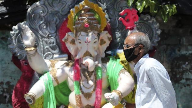 A man wearing a face masks walks past an idol of elephant-headed Hindu god Ganesha during reimposed weekend lockdown to prevent the spread of the coronavirus in Jammu, India.(AP) A man wearing a face masks walks past an idol of elephant-headed Hindu god Ganesha during reimposed weekend lockdown to prevent the spread of the coronavirus in Jammu, India.(AP)