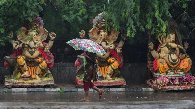 A woman walks past Ganesh idols placed along a road during rains in New Delhi on August 19. Peak rains were witnessed in August this year as a result, and especially the last week. Indian Meteorological Department (IMD) scientists told HT that with another week of rain forecast for Delhi, this August will likely catch up to become the wettest compared to at least the last five years. (Manvender Vashist / PTI)