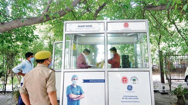 A health worker inside a kiosk collects swab samples for coronavirus test, at Sector 30 District Hospital, in Noida.(Photo: Sunil Ghosh/ HT)