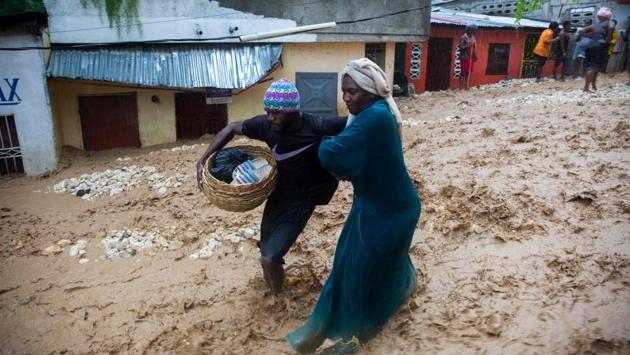 People selling from the market walk in the flooded street in the neighbourhood of Pétion ville in Haiti on August 23 during the passage of tropical storm Laura. The weather system churned just south of Cuba after killing at least 24 people in the Dominican Republic and Haiti, where it knocked out power and caused flooding in the two nations. (Estailove ST-VAL / AFP)