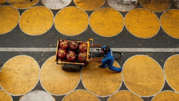 A man pushes a cart filled with liquefied petroleum gas (LPG) cylinders on a street painted with circles in Mumbai.(REUTERS)