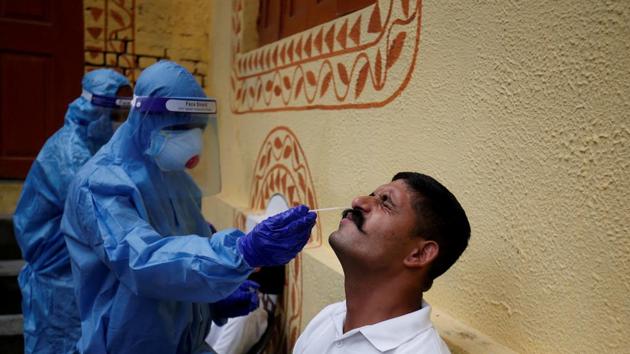 A healthcare worker wearing personal protective equipment (PPE) takes a swab from a police officer for a rapid antigen test at a special testing center for Gujarat Police, amid the coronavirus disease outbreak, in Ahmedabad.(REUTERS) A healthcare worker wearing personal protective equipment (PPE) takes a swab from a police officer for a rapid antigen test at a special testing center for Gujarat Police, amid the coronavirus disease outbreak, in Ahmedabad.(REUTERS)