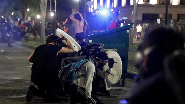 People take cover during a protest in Kenosha, Wisconsin on August 25. The protests entered a third day on August 25, with hundreds of protesters gathering as they defied curfew, threw bottles and shot fireworks at law enforcement guarding the courthouse. (Brendan McDermid / REUTERS) People take cover during a protest in Kenosha, Wisconsin on August 25. The protests entered a third day on August 25, with hundreds of protesters gathering as they defied curfew, threw bottles and shot fireworks at law enforcement guarding the courthouse. (Brendan McDermid / REUTERS)