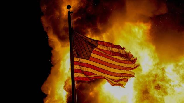 A flag flies over a department of corrections building that was on fire during protests in Kenosha, Wisconsin on August 24. Wisconsin Governor Tony Evers called for calm on August 25, while also declaring a state of emergency under which he doubled the National Guard deployment in Kenosha from 125 to 250. (AP / PTI) A flag flies over a department of corrections building that was on fire during protests in Kenosha, Wisconsin on August 24. Wisconsin Governor Tony Evers called for calm on August 25, while also declaring a state of emergency under which he doubled the National Guard deployment in Kenosha from 125 to 250. (AP / PTI)