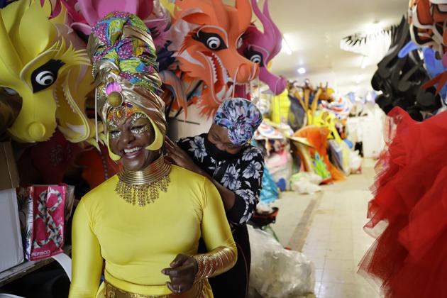 Anucska Case assists Carolyn Roberts-Griffith, left, with her costume for a prepping event ahead of this years Notting Hill Carnival which will be held virtually, in London, Thursday, Aug. 20, 2020. London's Notting Hill Carnival traces its roots to the emancipation of Black slaves and race riots in the city during the late 1950s. Organizers say the event is more important than ever amid the worldwide campaign for justice following the death of George Floyd in police custody. But their message of resistance and reconciliation will be delivered online worldwide this weekend after the COVID-19 pandemic forced the party to reinvent itself as a virtual event. (AP Photo/Kirsty Wigglesworth) (AP) Anucska Case assists Carolyn Roberts-Griffith, left, with her costume for a prepping event ahead of this years Notting Hill Carnival which will be held virtually, in London, Thursday, Aug. 20, 2020. London's Notting Hill Carnival traces its roots to the emancipation of Black slaves and race riots in the city during the late 1950s. Organizers say the event is more important than ever amid the worldwide campaign for justice following the death of George Floyd in police custody. But their message of resistance and reconciliation will be delivered online worldwide this weekend after the COVID-19 pandemic forced the party to reinvent itself as a virtual event. (AP Photo/Kirsty Wigglesworth) (AP)