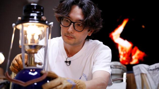 Lee Seung-yoon lights a lamp during his staycation in Seoul. To enhance the outdoor experience Seung-yoon added a crackling campfire video stream on the television which furthered the “atmosphere of authenticity.” (Kim Hong-Ji / REUTERS)