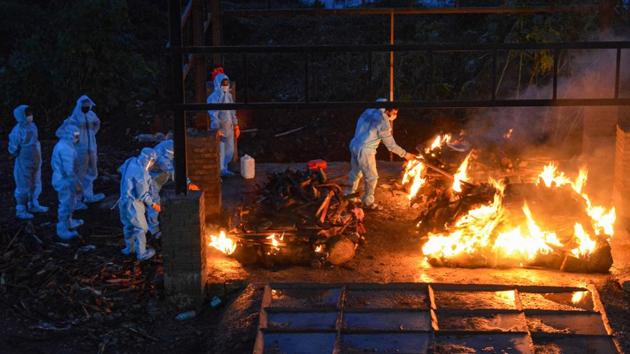 Municipal workers and family members wearing protective suits cremate the body of a Covid-19 patient at a crematorium in Karad on August 24. Meanwhile on August 27, the country also recorded 1,023 fatalities in the last 24 hours which pushed the death toll to 60,472, HT reported from Health Ministry’s bulletin. (PTI) 