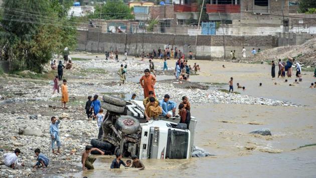Children seen atop an overturned vehicle after flash floods swept through the area in Jalalabad on August 26. The flash floods were triggered by exceptionally heavy rain this week. (Noorullah Shirzada / AFP)