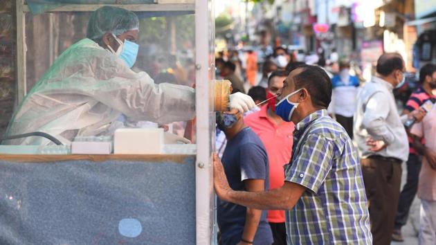A health official collects a swab sample from a coronavirus testing kiosk set at a weekly market in Pandav Nagar, in New Delhi on Wednesday.(Raj K Raj/HT Photo)