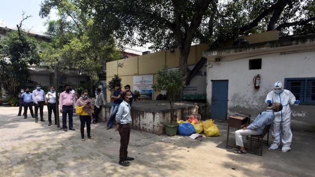 A health worker collects swab sample from a man for coronavirus rapid antigen and RT-PCR testing, at Ramjas School, in Daryaganj.(Sonu Mehta/HT PHOTO)