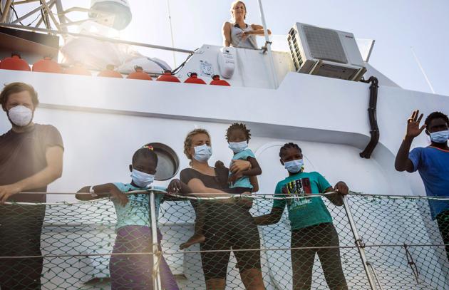 Crew members and rescued workers stand on the deck of the Louise Michel rescue vessel, a French patrol boat currently manned by activists and funded by the renowned artist Banksy in the Central Mediterranean sea, at 50 miles south from Lampedusa, , Friday, Aug. 28, 2020.  (AP) 
