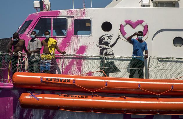 A boy waves to the crew of the Astral rescue vessel from the deck of the Louise Michel rescue vessel, a French patrol boat currently manned by activists and funded by the renowned artist Banksy in the Central Mediterranean sea, at 50 miles south from Lampedusa, Friday, Aug. 28, 2020. (AP) 