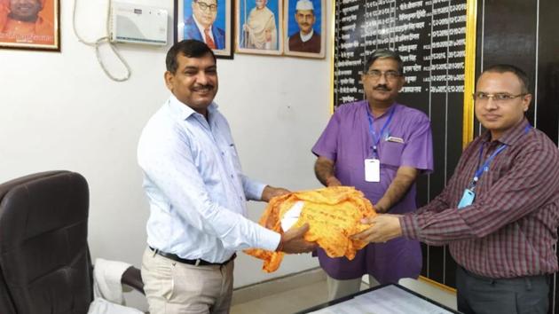Dr Anil Mishra, member of the Trust (in middle) handing over layout of Ram Mandir to vice chairman of Ayodhya Development Authority Neeraj Shukla ( white shirt) in his office on Aug 29, 2020. (HT Photo)