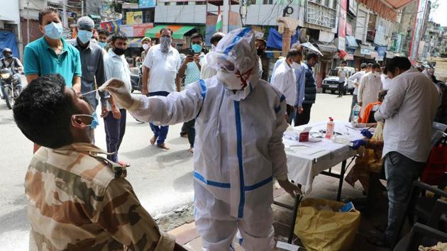 A medic collects swab sample from an ITBP jawan for Covid-19 test at Raghunath Bazaar in Jammu.(PTI)