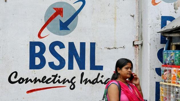 A woman speaks on her mobile phone in front of the logo of Bharat Sanchar Nigam Ltd (BSNL) painted on a wall outside its office in Kolkata.(REUTERS)