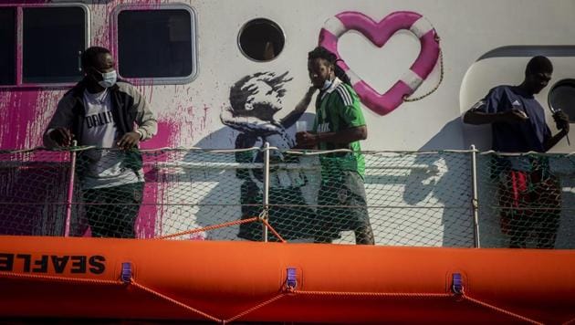 A man walks past a painting by British artist Banksy on the deck of the Louise Michele rescue vessel, after performing 2 rescue operations on the high seas in the past days, 70 miles south west Malta, Central Mediterranean sea, Saturday, Aug. 29, 2020. A rescue ship painted and sponsored by British artist Banksy saved another 130 migrants stranded on a rubber boat in the Southern Mediterranean Sea.(AP)