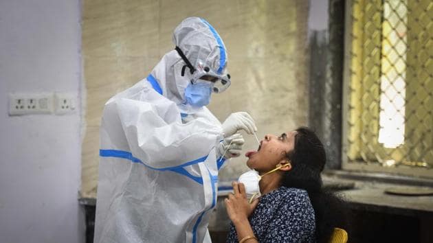 A healthcare worker collects a swab sample from a woman for coronavirus testing, in New Delhi on Friday.(Sanchit Khanna/HT Photo)