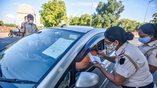 Delhi Police personnel checks a commuter for violating rules by not wearing face mask in public, at India Gate, in New Delhi.(Biplov Bhuyan/HT PHOTO)