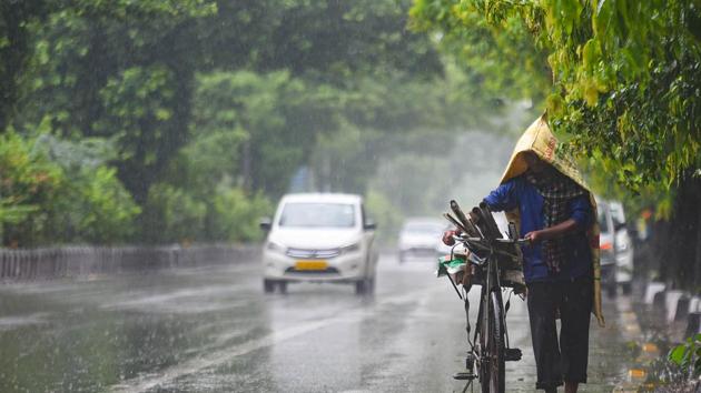 File photo: A commuter pushes his cycle under heavy rain near.(Amal KS/HT PHOTO)
