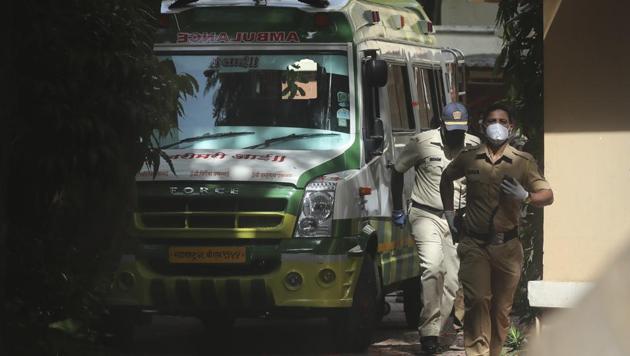 Policemen walk near an ambulance carrying the body of Bollywood actor Sushant Singh Rajput before it leaves from the building he lived in Mumbai.(AP)