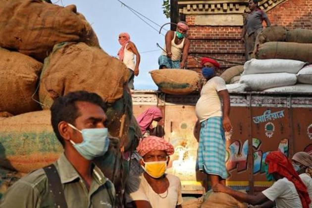 Labourers wearing protective face masks load grocery items onto a supply truck at a wholesale market during the coronavirus disease (COVID-19) outbreak in Kolkata.(REUTERS)