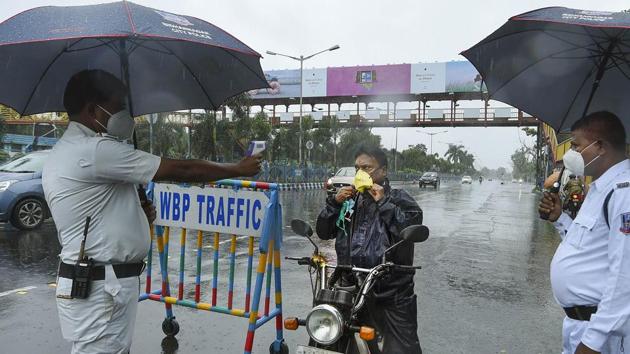 Kolkata: A police constable uses a thermal screening device on a commuter amid rain during the biweekly lockdown in the wake of Covid-19 pandemic.(PTI)