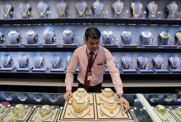 A salesman displays gold necklaces and earrings inside a jewellery showroom in Mumbai in this file photo. Gold prices in India had hit a record high of <span class='webrupee'>?</span>56,200 on August 7 and have been volatile since then following global rates.(Reuters Photo)