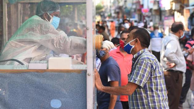 A health official collects a swab sample from a coronavirus testing kiosk set at a weekly market in Pandav Nagar, in New Delhi.(Raj K Raj/HT PHOTO)