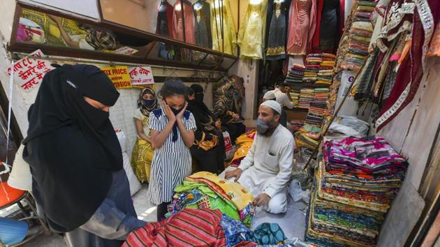 Customers interact with a shopkeeper at a garment store in Old Delhi.(PTI)