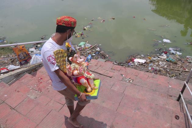 An Indian man wearing a mask as a precaution against the coronavirus carries an idol of elephant-headed Hindu god Ganesha to immerse in Saroornagar Lake on the final day of Ganesh Chaturthi festival in Hyderabad, India, Tuesday, Sept. 1, 2020. The festival is a celebration of the birth of Ganesha, the Hindu god of wisdom, prosperity and good fortune. (AP Photo/Mahesh Kumar A.) (AP)