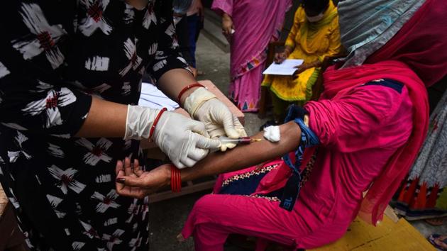 A healthcare worker takes blood sample from a person for use in the third round of serological survey testing for Covid-19, in New Delhi on Wednesday.(Sanchit Khanna/HT Photo)