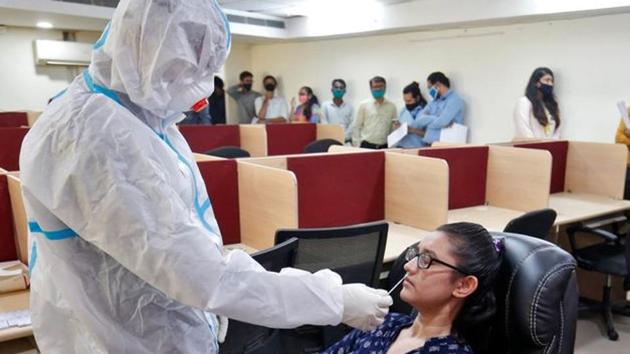 A healthcare worker wearing personal protective equipment (PPE) takes a swab from a woman for a rapid antigen test inside an office. (REUTERS)