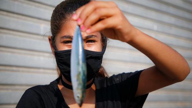 A Palestinian girl wearing a face mask due to the Covid-19 pandemic, holds a fish at the seaport at Gaza Seaport on September 3. Amid old politics and a new pandemic the territory’s fish markets which have been virtually empty of late, are now expecting the return of Palestinians buying fresh sea bream and sardines. (Mohammed Abed / AFP) A Palestinian girl wearing a face mask due to the Covid-19 pandemic, holds a fish at the seaport at Gaza Seaport on September 3. Amid old politics and a new pandemic the territory’s fish markets which have been virtually empty of late, are now expecting the return of Palestinians buying fresh sea bream and sardines. (Mohammed Abed / AFP)