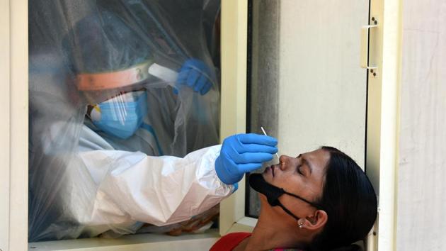 A woman gives a swab sample for coronavirus testing at a hospital in Defence Colony.(Sonu Mehta/HT photo)