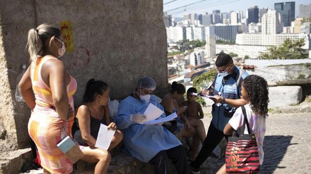 A city health worker waits for the results of a resident's rapid Covid-19 test in Rio de Janeiro during new program that aims to identify the percentage of infected people inside communities and plan the return of economic activities and services on September 3. (Silvia Izquierdo / AP) A city health worker waits for the results of a resident's rapid Covid-19 test in Rio de Janeiro during new program that aims to identify the percentage of infected people inside communities and plan the return of economic activities and services on September 3. (Silvia Izquierdo / AP)