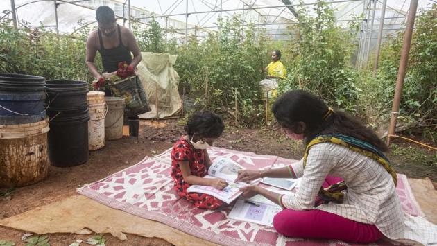 Shital Sonawane (R), a volunteer associated with the Zila Parishad school teaches Sushmita Sontakke (L), a Class 1 student at a nursery as Sontakke’s parents Savita and Mahendra work in the background, at Kalamshet village on September 4. Sonawane teaches five students and she visits them individually at their homes on alternate days. (Pratham Gokhale / HT Photo) 