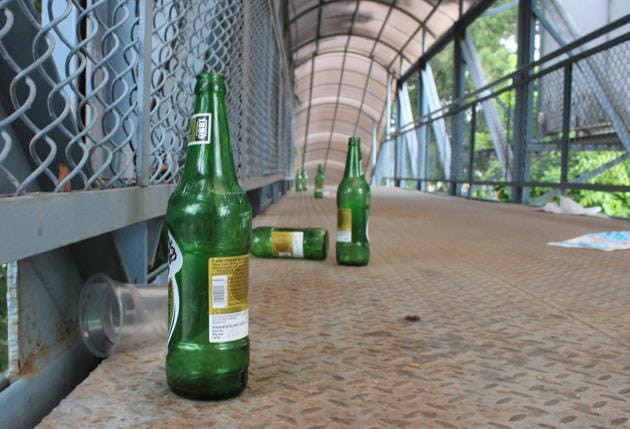 Beer bottles, waste lie scattered on a foot overbridge in Mohali.(HT Photo)