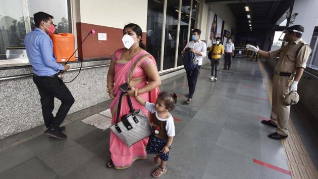 A worker sanitizes commuters’ luggage while a CISF personnel ensures social distancing in maintained at the Chattarpur Metro Station in New Delhi on September 7. The Home Ministry, in its Unlock 4 guidelines, gave a nod to the return of metro services from September 7 in a graded manner. Services on the DMRC network were suspended in March due to Covid-19. (Sanjeev Verma / HT Photo)