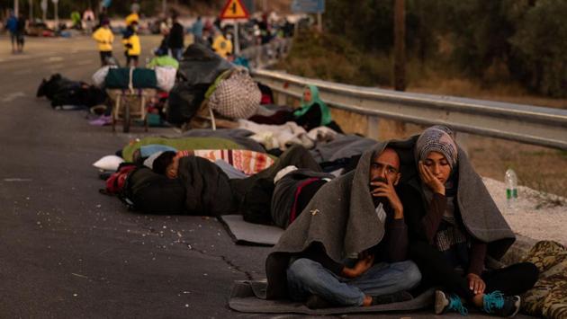 A couple sits under a blanket on a road following a fire at the Moria camp on the island of Lesbos on September 10. Thousands of asylum seekers on Lesbos were seen camping on roadsides. Desperate families, many with young children, spent a second night in the open, many without tents or even basic bedding. (Alkis Konstantinidis / REUTERS) A couple sits under a blanket on a road following a fire at the Moria camp on the island of Lesbos on September 10. Thousands of asylum seekers on Lesbos were seen camping on roadsides. Desperate families, many with young children, spent a second night in the open, many without tents or even basic bedding. (Alkis Konstantinidis / REUTERS)
