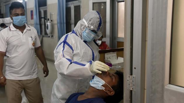 A health worker collects a swab sample from a man for coronavirus testing, at Sarojini Nagar Dispensary, in New Delhi.(Sanjeev Verma/HT PHOTO)